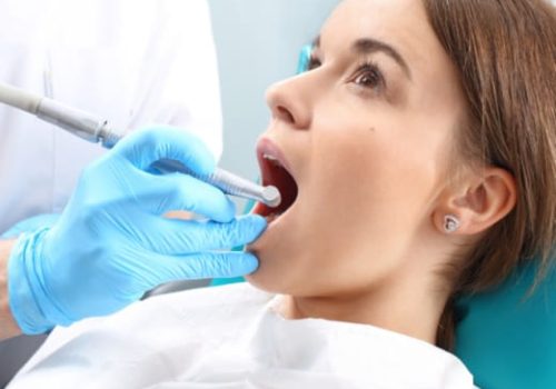 Dentist examines woman’s open mouth during dental check-up.