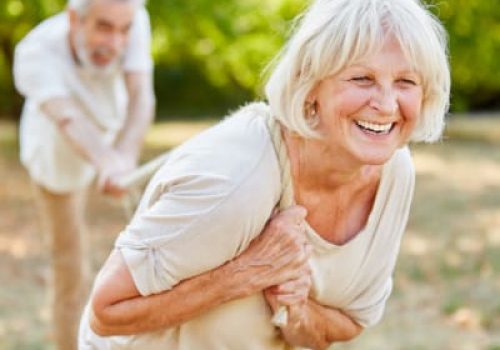 Older couple smiling while playing tug-of-war outdoors.